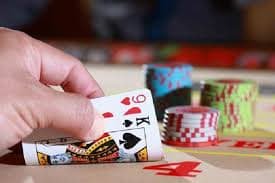 Dealer ras toto menangani kartu di meja blackjack hijau dengan kamera multi-sudut menangkap semua sudut tabel